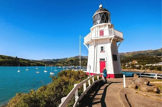 The white Akaroa lighthouse with a red door at Cemetery Point
